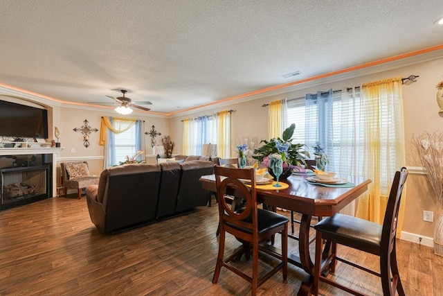 dining space with ceiling fan, dark wood-type flooring, a textured ceiling, and crown molding