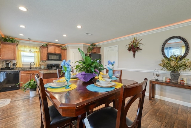 dining space with ornamental molding, sink, and hardwood / wood-style flooring