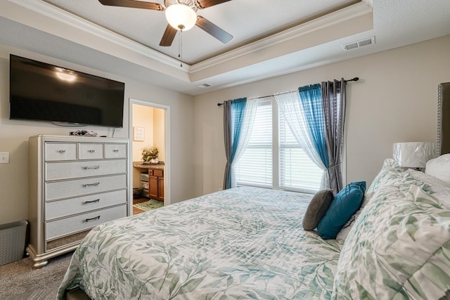 carpeted bedroom with connected bathroom, ornamental molding, ceiling fan, and a raised ceiling