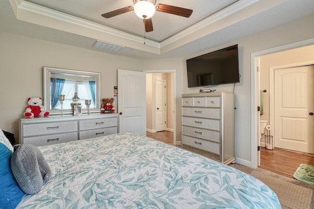 bedroom featuring ceiling fan, light hardwood / wood-style flooring, a tray ceiling, and ornamental molding