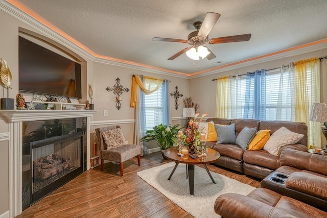 living room featuring a tiled fireplace, a wealth of natural light, ornamental molding, and hardwood / wood-style floors