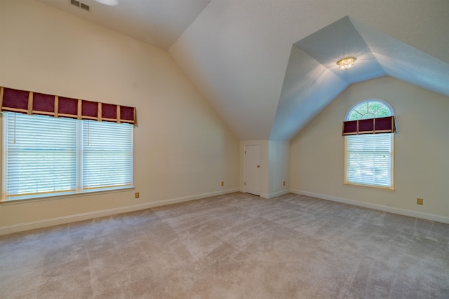 additional living space with light carpet and vaulted ceiling