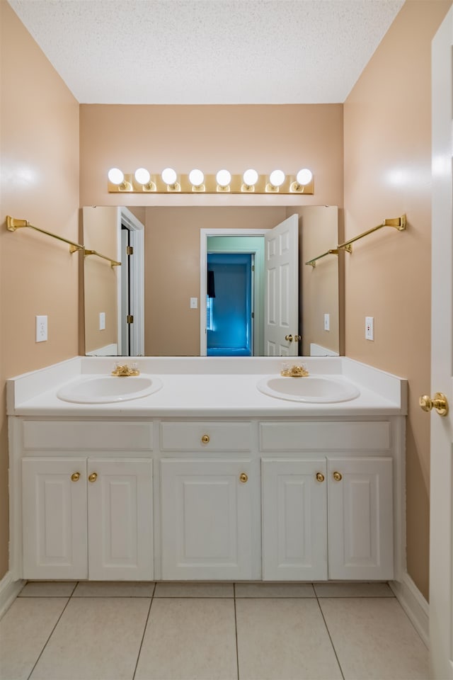 bathroom with a textured ceiling, dual vanity, and tile patterned flooring