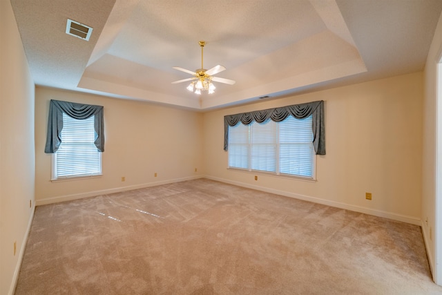 spare room featuring light colored carpet, ceiling fan, and a raised ceiling