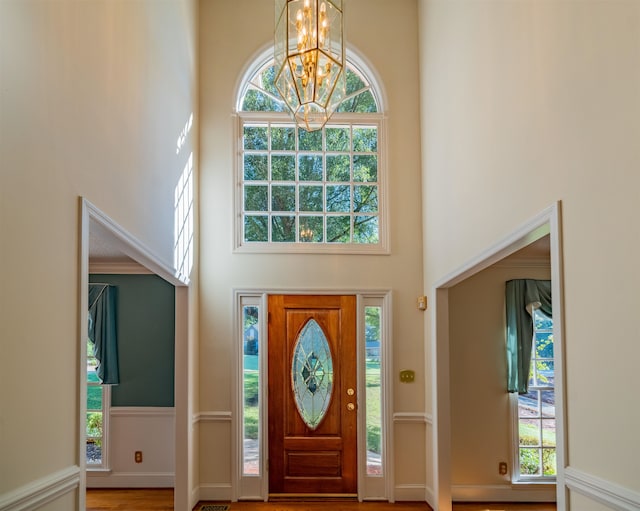 entrance foyer with hardwood / wood-style flooring, an inviting chandelier, and a towering ceiling