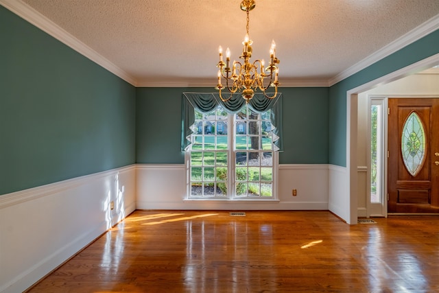 entrance foyer featuring a textured ceiling, an inviting chandelier, crown molding, and wood-type flooring