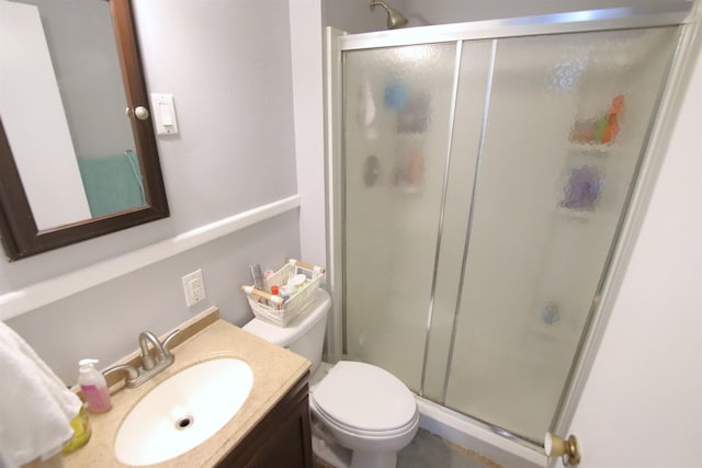 bathroom with vanity, a shower with door, and toilet