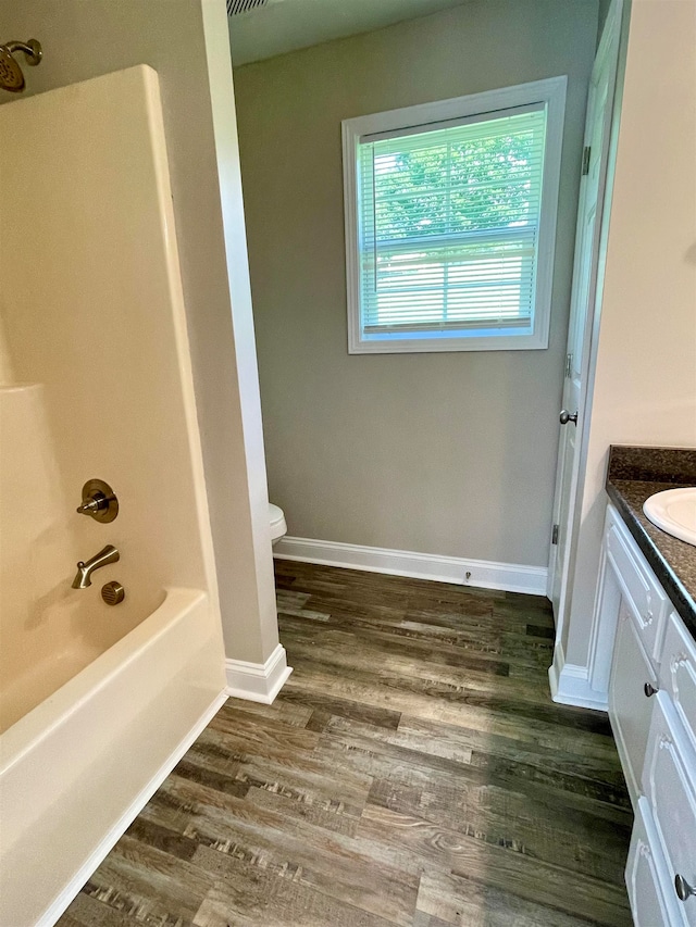 full bathroom featuring washtub / shower combination, toilet, vanity, and wood-type flooring