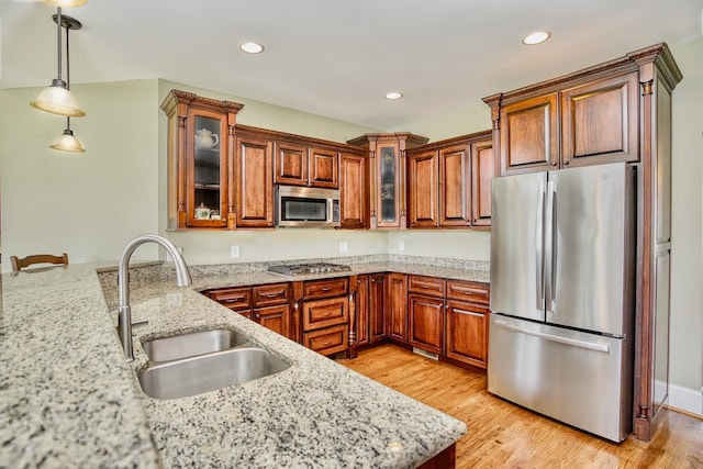 kitchen with light wood-type flooring, stainless steel appliances, sink, and decorative light fixtures