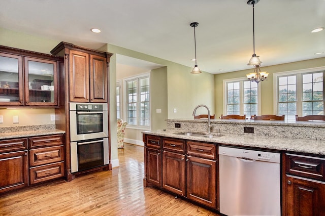 kitchen featuring hanging light fixtures, a notable chandelier, light wood-type flooring, stainless steel appliances, and sink