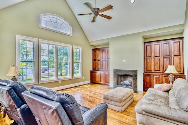 living room with ceiling fan, high vaulted ceiling, and light hardwood / wood-style flooring