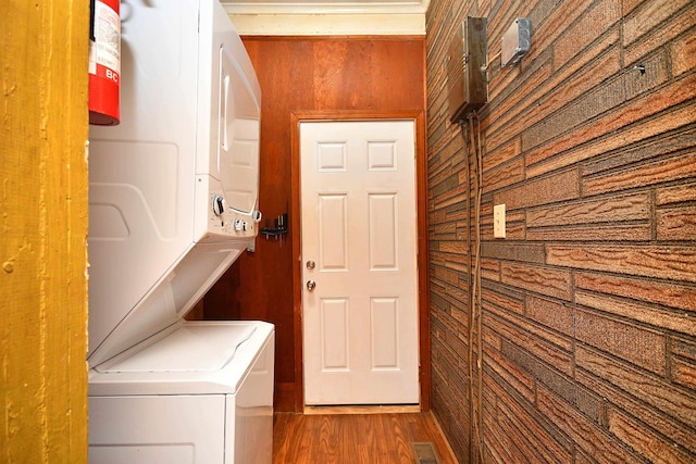 clothes washing area with stacked washing maching and dryer and dark hardwood / wood-style flooring