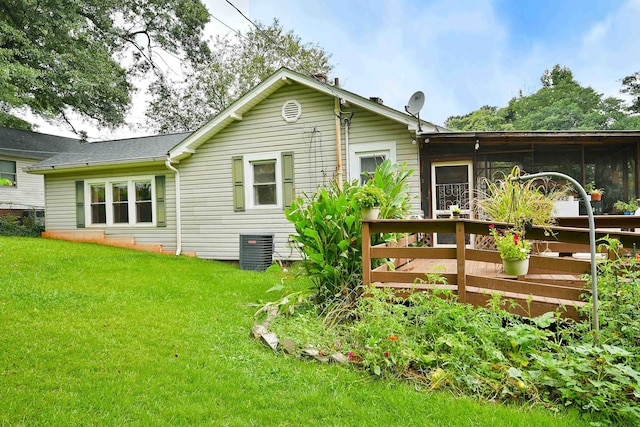 rear view of property with central AC unit and a yard