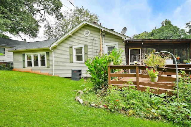 rear view of house with central air condition unit, a yard, and a sunroom