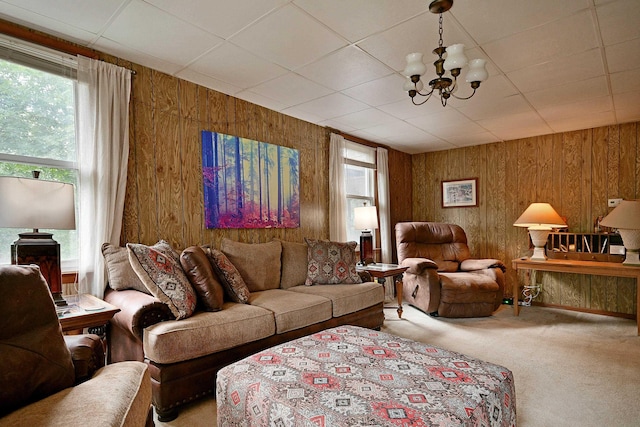 carpeted living area featuring a notable chandelier and wooden walls