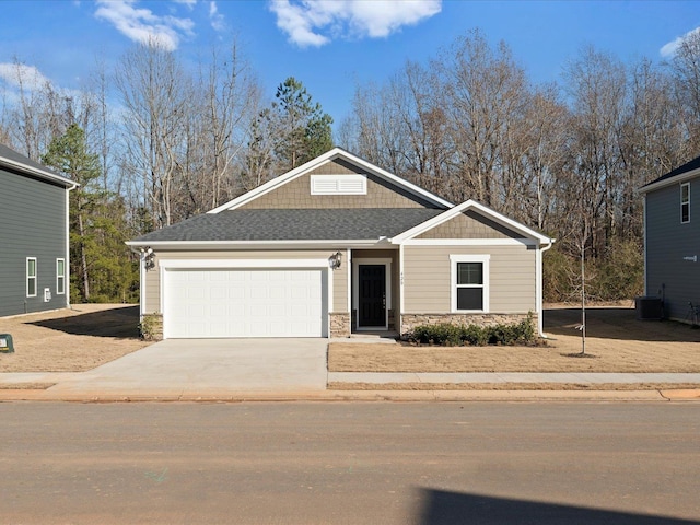 craftsman house featuring roof with shingles, concrete driveway, an attached garage, central AC, and stone siding