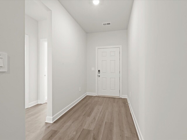 hallway featuring baseboards, visible vents, and wood finished floors