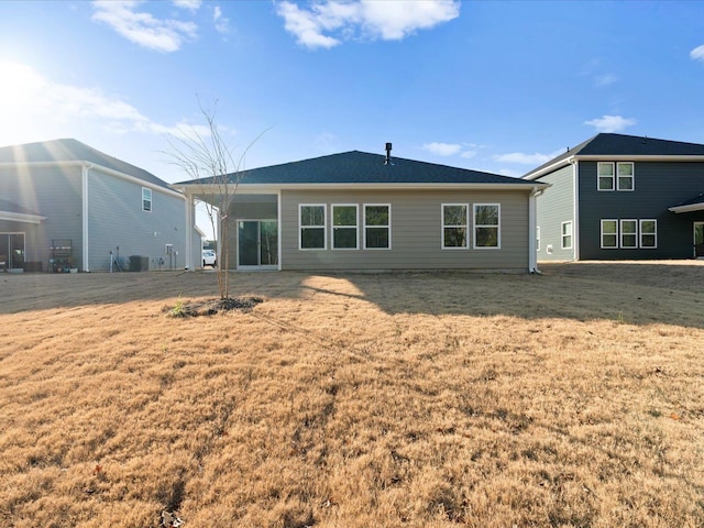 back of house featuring a lawn and central air condition unit