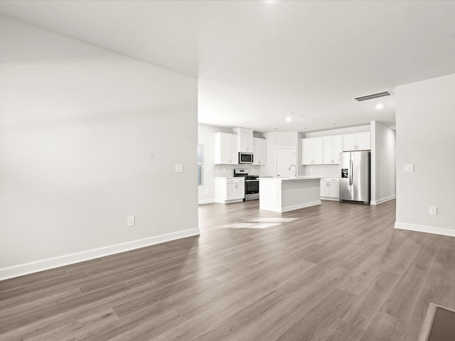 unfurnished living room with recessed lighting, wood finished floors, visible vents, and baseboards