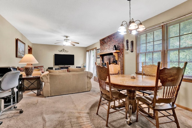 carpeted dining area featuring ceiling fan with notable chandelier, a healthy amount of sunlight, and brick wall