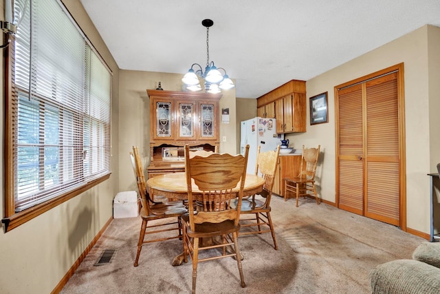 carpeted dining area featuring an inviting chandelier