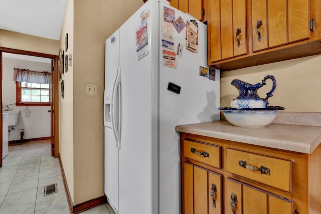 kitchen with sink, white refrigerator with ice dispenser, and light tile patterned floors