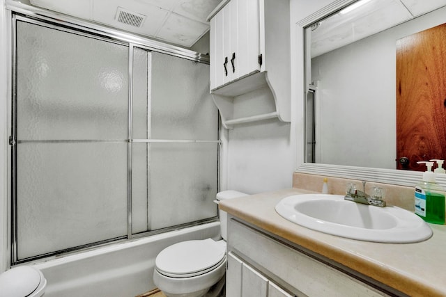 full bathroom featuring enclosed tub / shower combo, vanity, and toilet