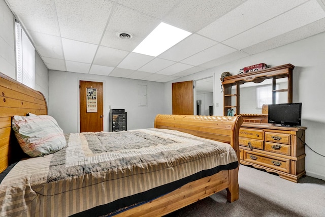 carpeted bedroom with a paneled ceiling and electric panel