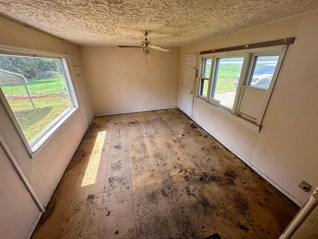 unfurnished dining area featuring ceiling fan, a textured ceiling, and wood finished floors