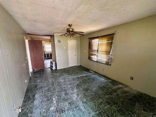 unfurnished room with ceiling fan and a textured ceiling