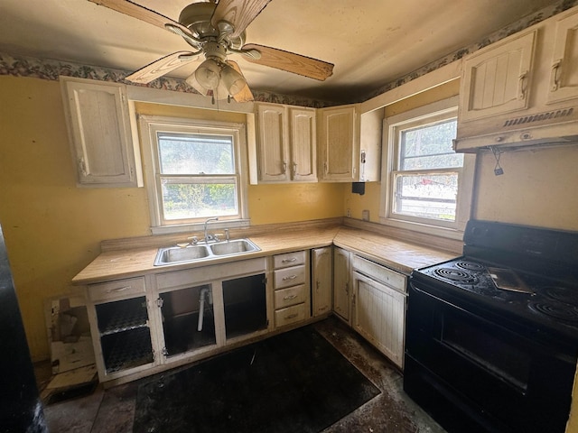 kitchen with black electric range, a wealth of natural light, light countertops, a sink, and under cabinet range hood