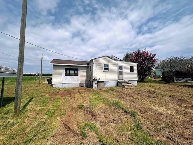 back of house featuring entry steps and a yard