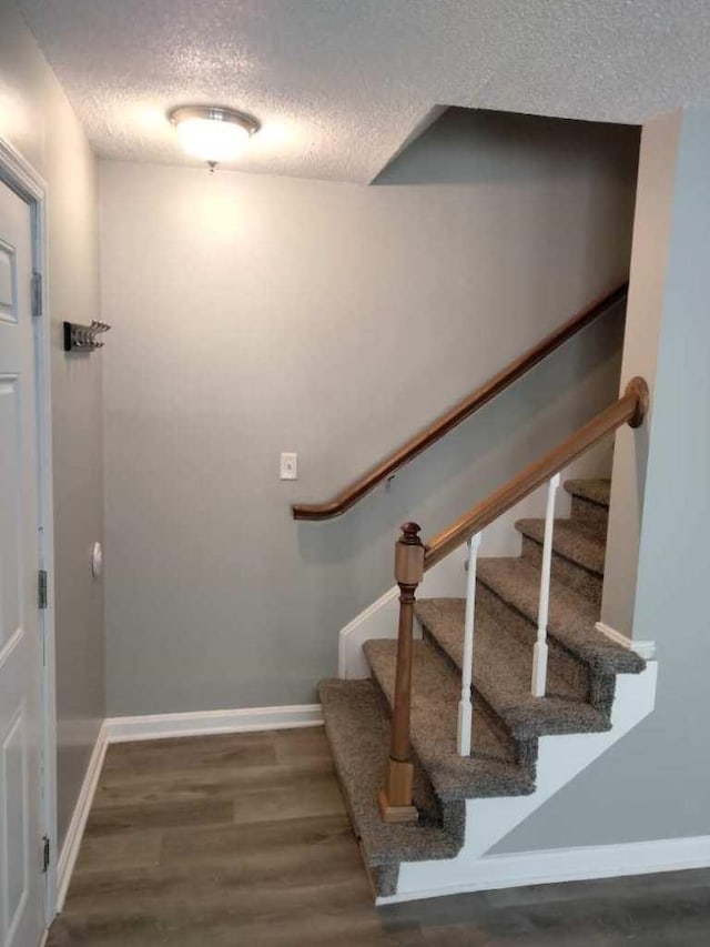 stairway with a textured ceiling and hardwood / wood-style flooring