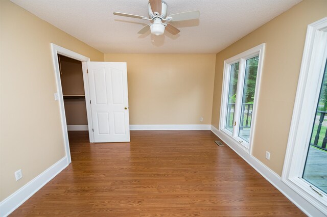 spare room featuring a wealth of natural light, hardwood / wood-style floors, and ceiling fan