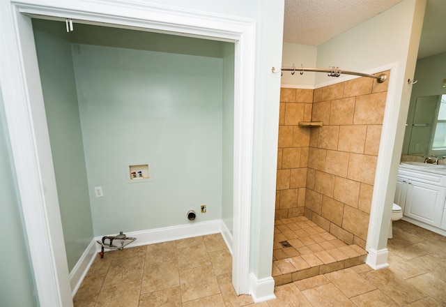 bathroom with a tile shower, a textured ceiling, tile patterned flooring, vanity, and toilet