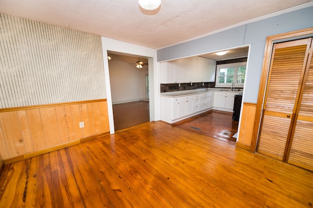 unfurnished living room with ceiling fan, sink, hardwood / wood-style floors, and ornamental molding