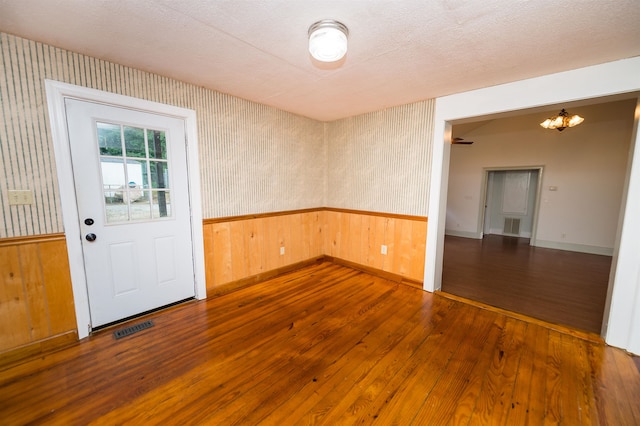 spare room with hardwood / wood-style flooring, a textured ceiling, and a chandelier