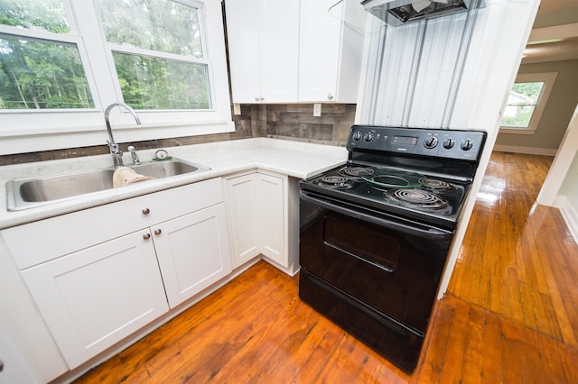 kitchen with sink, black electric range, wood-type flooring, decorative backsplash, and white cabinets