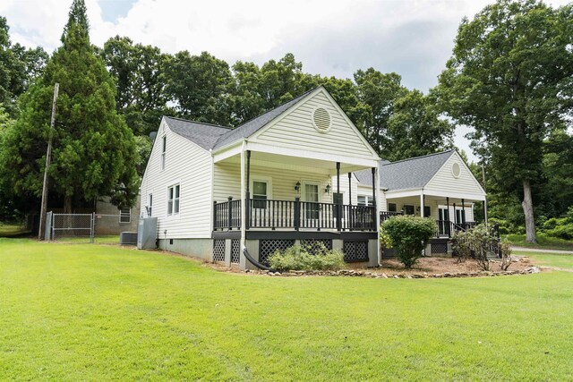 view of front of home featuring a front yard, central AC, and covered porch