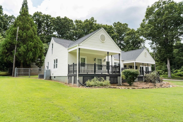 view of front of property with covered porch, central AC, fence, and a front lawn