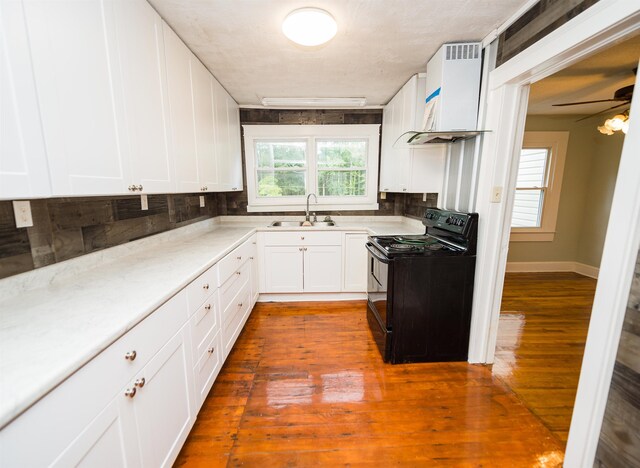 kitchen featuring custom range hood, backsplash, black electric range, light wood-type flooring, and ceiling fan