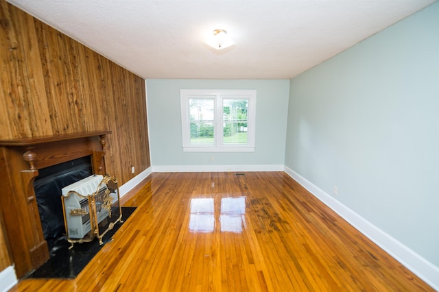 unfurnished living room featuring wood walls, hardwood / wood-style flooring, and a fireplace