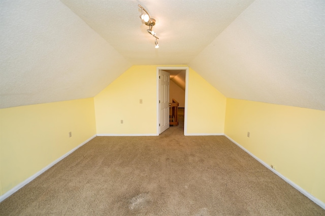 bonus room with light colored carpet, vaulted ceiling, and a textured ceiling