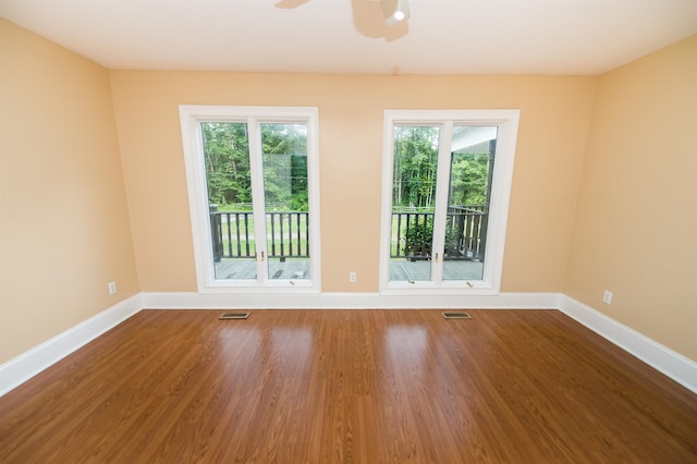 empty room with hardwood / wood-style floors, a wealth of natural light, and ceiling fan