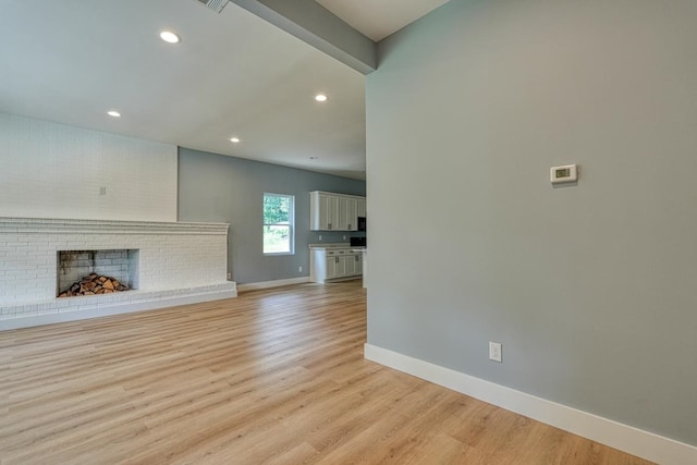 unfurnished living room featuring light wood-type flooring and a brick fireplace