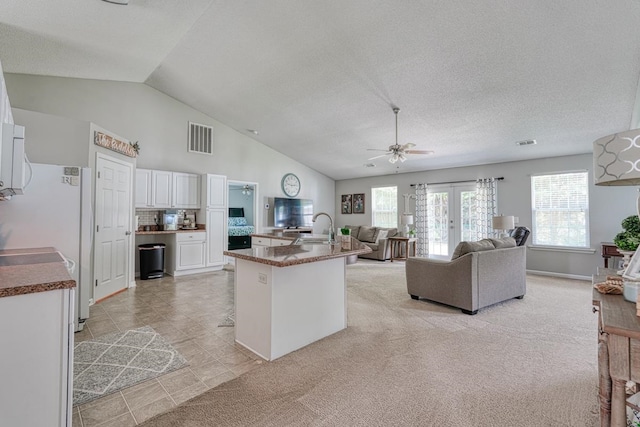 kitchen with ceiling fan, lofted ceiling, light carpet, and white cabinets