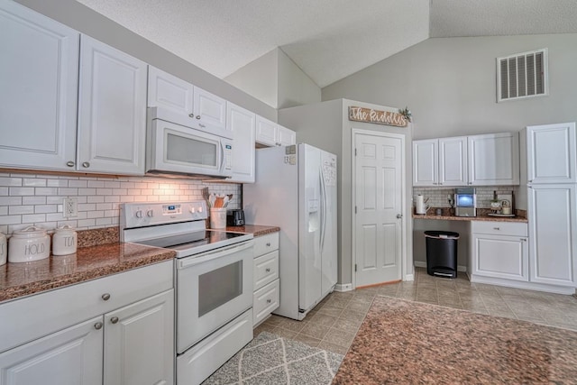 kitchen featuring backsplash, white cabinets, light tile patterned floors, lofted ceiling, and white appliances