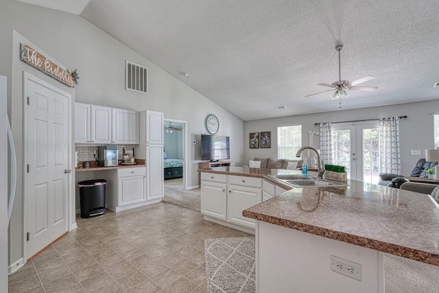 kitchen featuring ceiling fan, backsplash, white cabinetry, light tile patterned floors, and sink