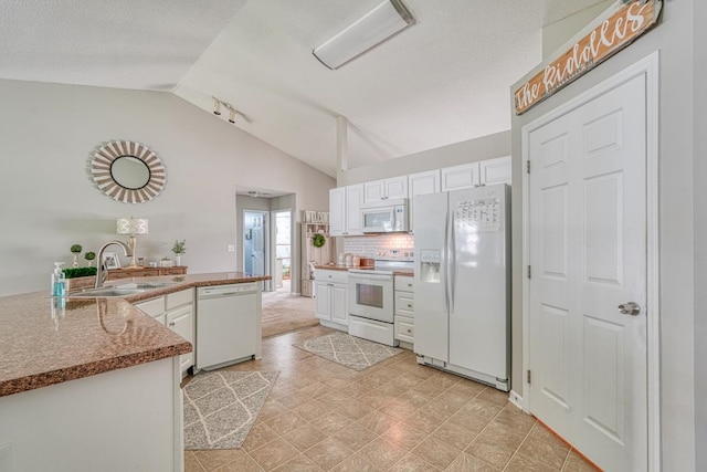 kitchen with sink, lofted ceiling, white appliances, light tile patterned floors, and white cabinets