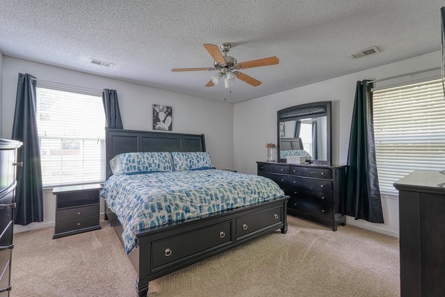 bedroom featuring a textured ceiling, ceiling fan, and light carpet